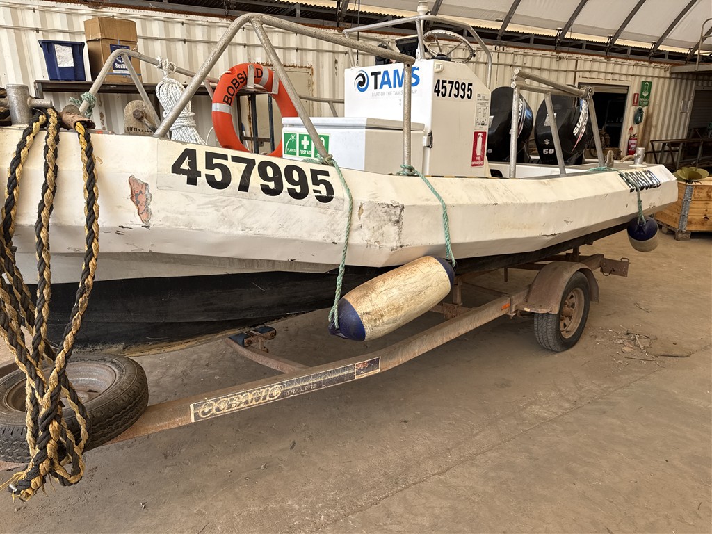 Small survey boat on trailer in a shed